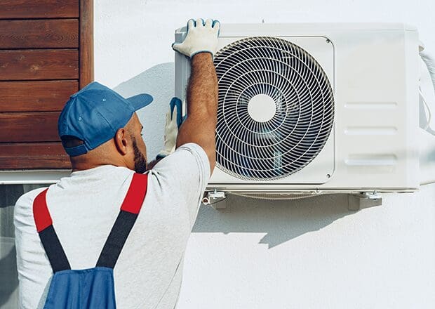 A man in blue gloves is fixing an air conditioner.