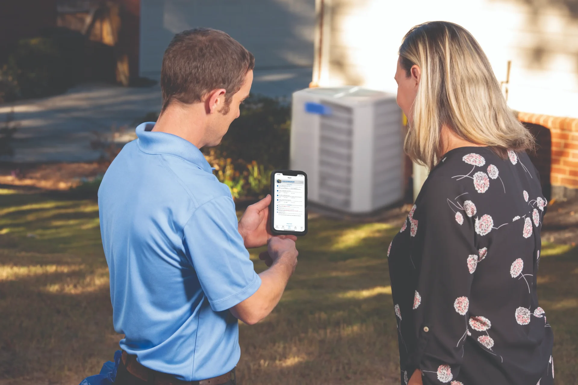 A man and woman looking at an air conditioner.